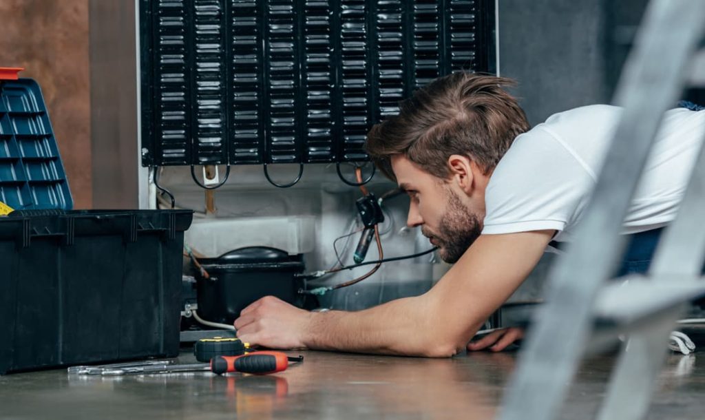 technician repairing commercial fridge